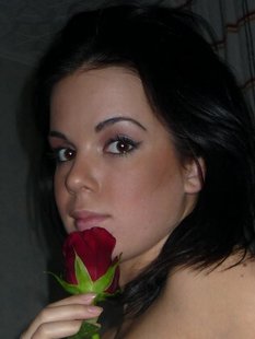Молодая брюнетка позирует дома с розой