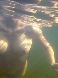 Кокетливая девушка купается в реке и греется на песочке